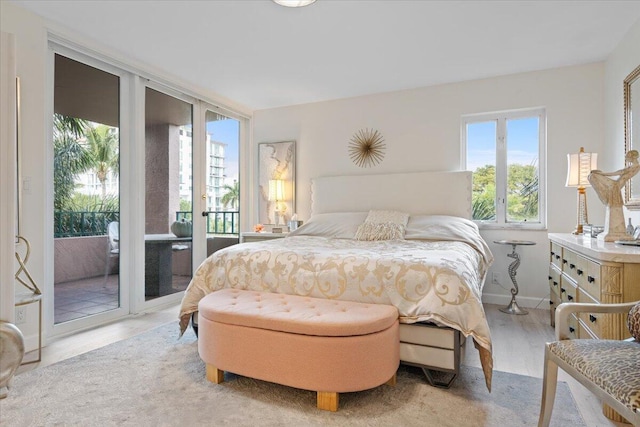 bedroom featuring a wall of windows, light wood-style flooring, baseboards, and access to exterior