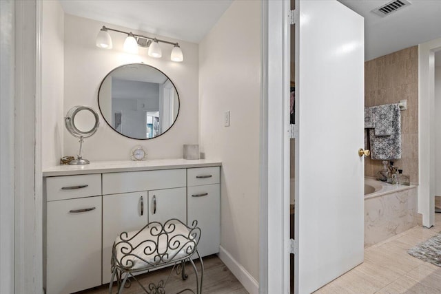 bathroom with visible vents, a bath, and vanity