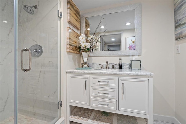 full bathroom featuring a marble finish shower, baseboards, and vanity