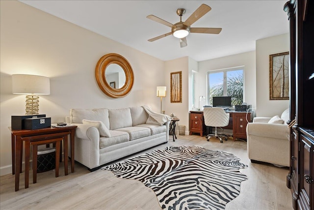 living area featuring light wood-style floors, baseboards, and ceiling fan