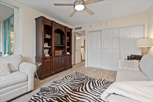 living room featuring visible vents, light wood-style flooring, and ceiling fan