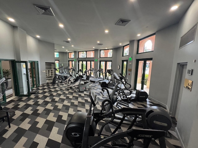 workout area with visible vents, french doors, baseboards, and a towering ceiling