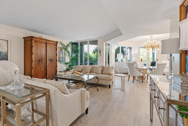 living room with a notable chandelier, light wood-style floors, and a healthy amount of sunlight