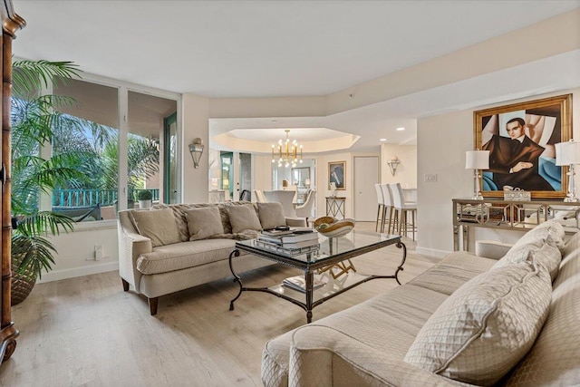 living room featuring baseboards, a chandelier, and light wood finished floors