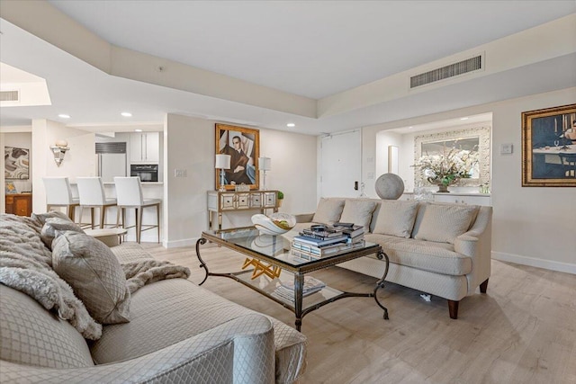 living room with light wood finished floors, visible vents, recessed lighting, and baseboards