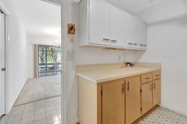 kitchen featuring a notable chandelier, baseboards, light colored carpet, and light countertops