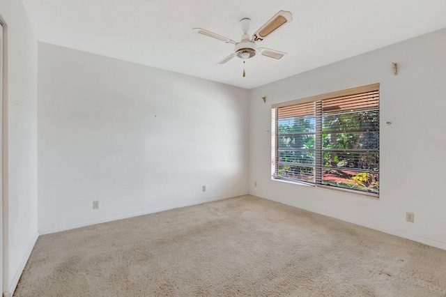 carpeted spare room featuring a ceiling fan and baseboards