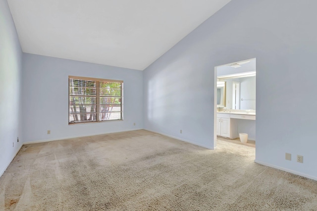 unfurnished room featuring built in study area, high vaulted ceiling, baseboards, and light carpet