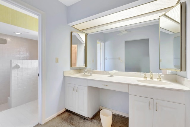 full bathroom with double vanity, walk in shower, baseboards, and a sink