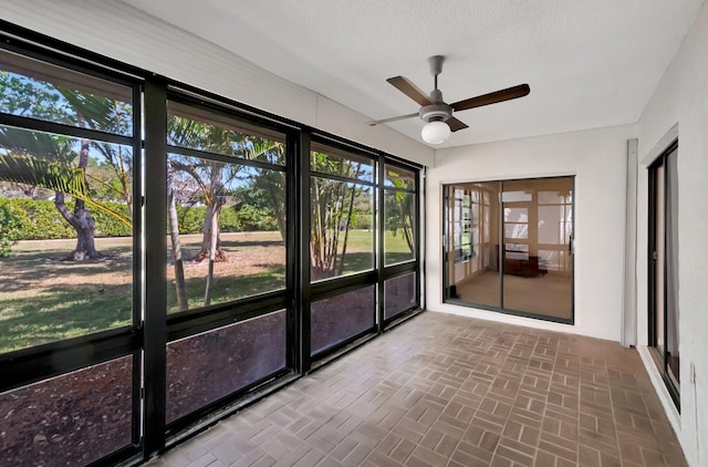 unfurnished sunroom featuring a ceiling fan