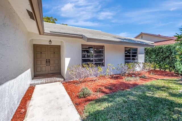 property entrance featuring a yard and stucco siding