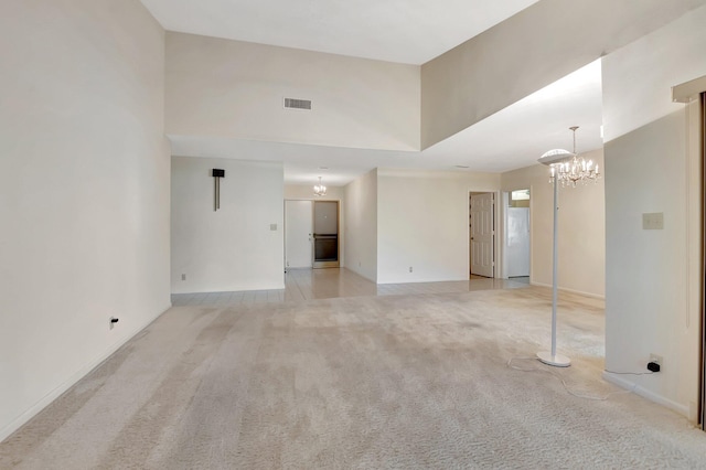 unfurnished living room featuring visible vents, light carpet, a notable chandelier, and a towering ceiling