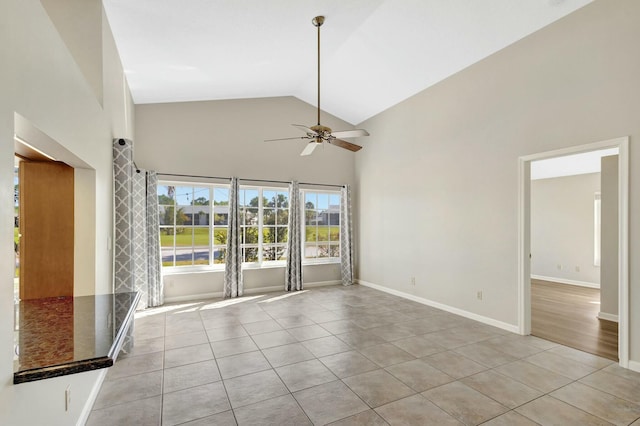 unfurnished room featuring light tile patterned floors, ceiling fan, high vaulted ceiling, and baseboards