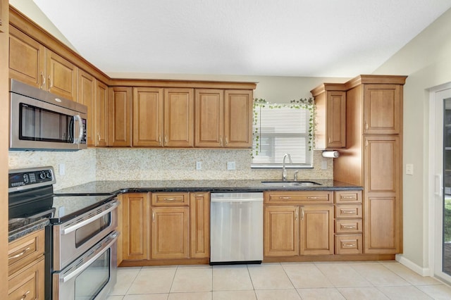 kitchen with light tile patterned floors, backsplash, stainless steel appliances, and a sink