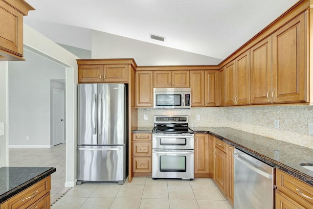 kitchen featuring visible vents, dark stone counters, appliances with stainless steel finishes, light tile patterned floors, and lofted ceiling