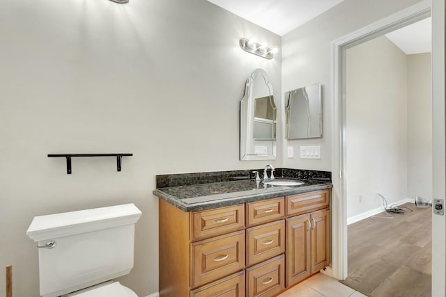 bathroom with vanity, toilet, and baseboards