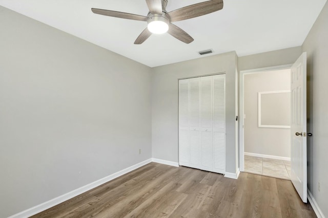 unfurnished bedroom featuring visible vents, baseboards, a closet, and wood finished floors