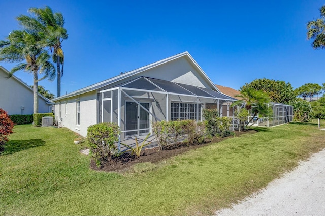 back of house featuring a lanai, stucco siding, cooling unit, and a yard