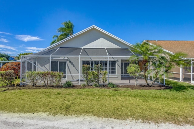 rear view of property featuring a lanai, stucco siding, and a yard