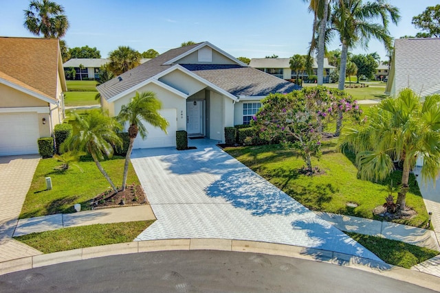 view of front of house with a front yard, an attached garage, a shingled roof, stucco siding, and decorative driveway