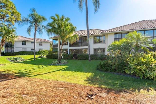 view of front of home featuring stucco siding, a front yard, and a tile roof