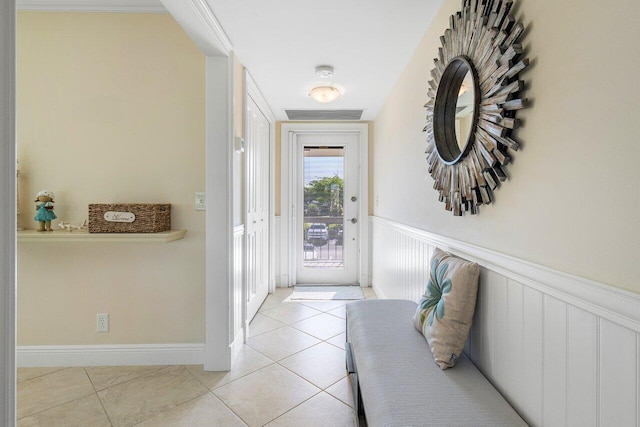 doorway featuring light tile patterned floors, a wainscoted wall, and visible vents