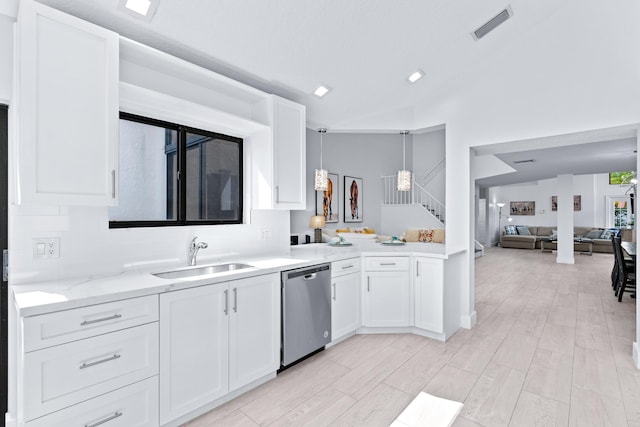 kitchen featuring visible vents, a sink, vaulted ceiling, white cabinets, and dishwasher