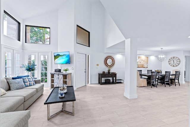 living room with light wood finished floors, baseboards, lofted ceiling, and an inviting chandelier