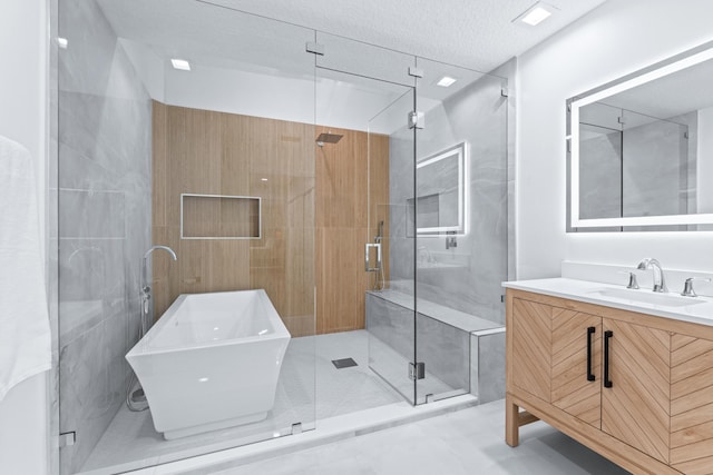 bathroom featuring vanity, a shower stall, a textured ceiling, and a freestanding bath