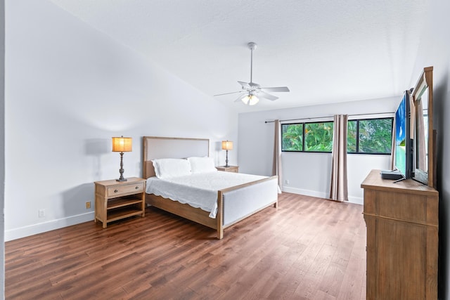 bedroom featuring baseboards, lofted ceiling, wood finished floors, and a ceiling fan