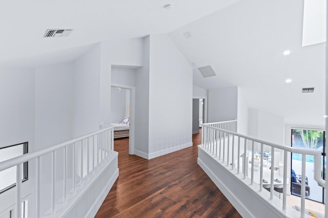 hallway with visible vents, an upstairs landing, lofted ceiling, and wood finished floors