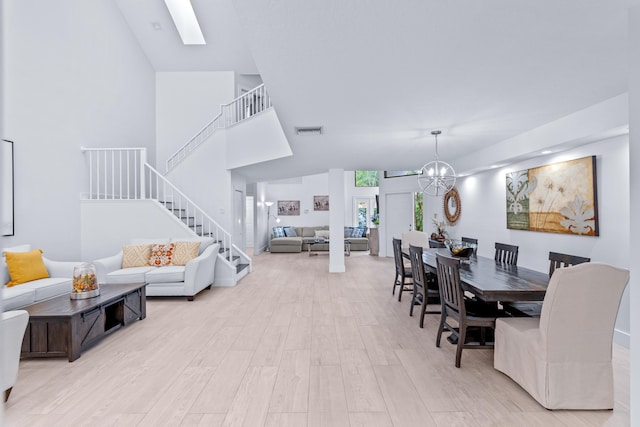 dining space with stairway, visible vents, light wood finished floors, an inviting chandelier, and a skylight