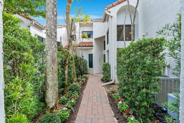 exterior space featuring stucco siding, central AC unit, and a tiled roof