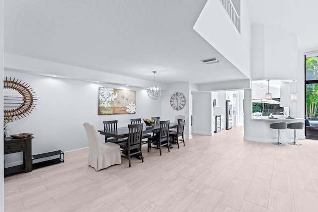 dining space with light wood-type flooring, baseboards, an inviting chandelier, and visible vents