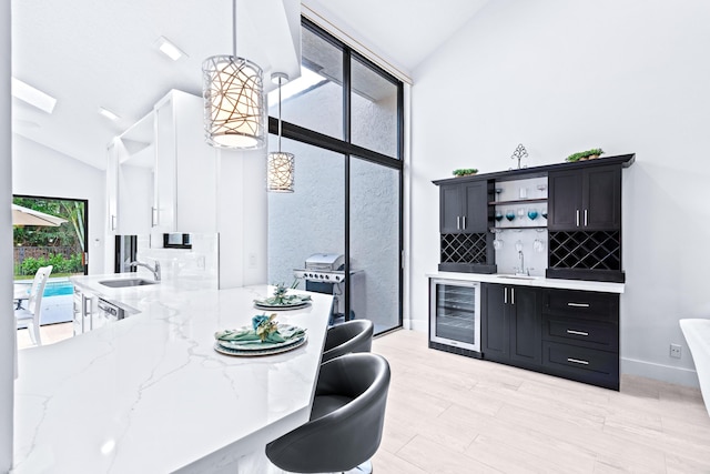 kitchen with wine cooler, dark cabinets, lofted ceiling, and open shelves