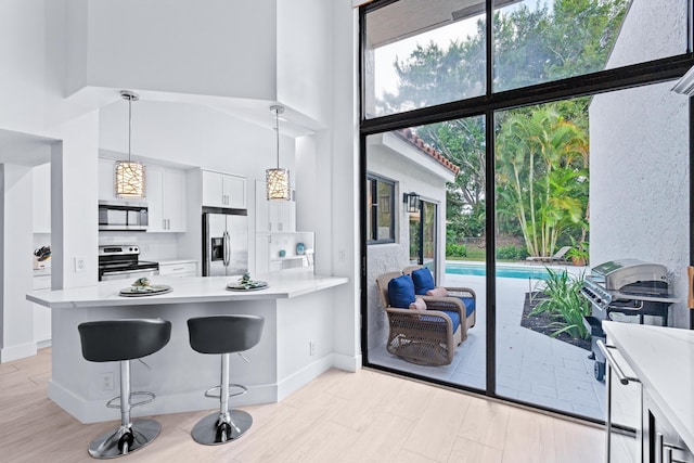 kitchen with appliances with stainless steel finishes, a peninsula, light countertops, and white cabinetry