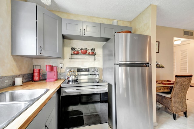 kitchen featuring visible vents, gray cabinetry, light countertops, appliances with stainless steel finishes, and a sink