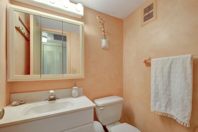 half bath with vanity, toilet, and visible vents