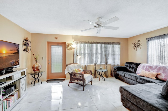 living room featuring light tile patterned floors, a textured ceiling, and ceiling fan