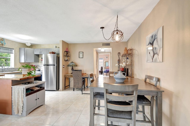 dining area featuring visible vents, a textured ceiling, and light tile patterned flooring