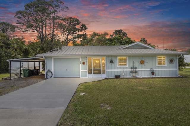 view of front of home with a garage, metal roof, driveway, and a front lawn