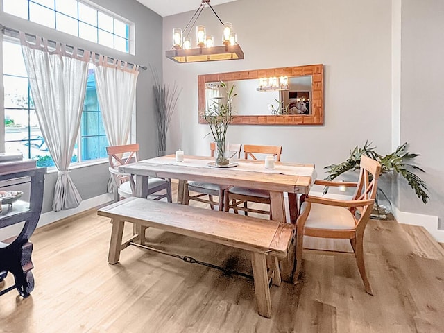 dining area with light wood-style flooring, baseboards, and an inviting chandelier