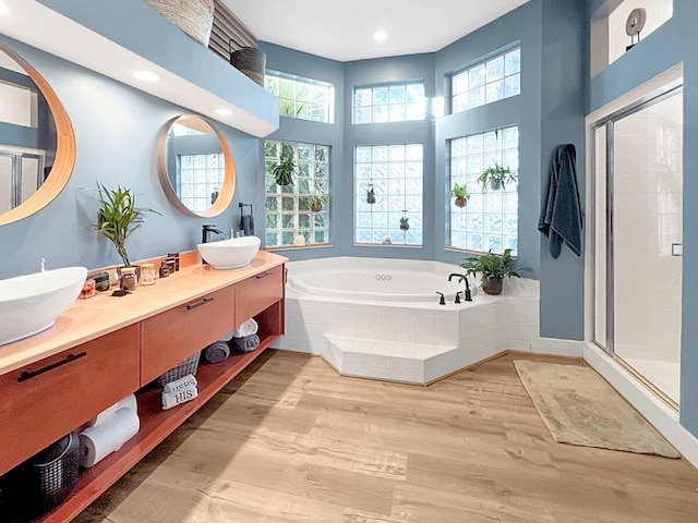 full bath featuring a stall shower, wood finished floors, a sink, and a bath