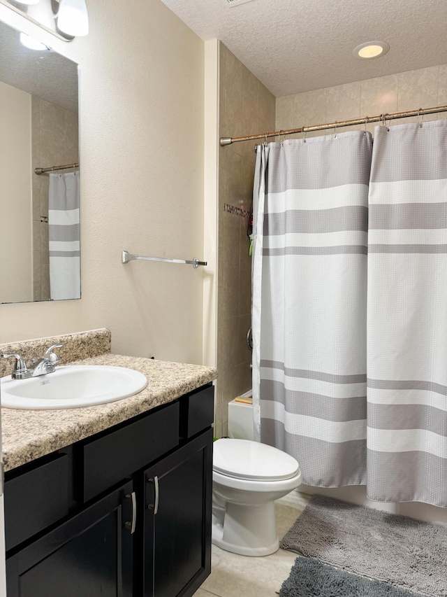 bathroom featuring a textured ceiling, tile patterned flooring, toilet, vanity, and shower / bath combo with shower curtain