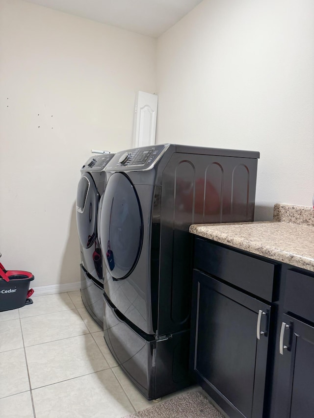 clothes washing area featuring light tile patterned floors, baseboards, cabinet space, and washer and dryer