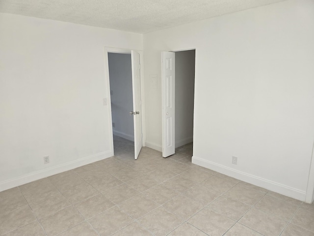 unfurnished room with baseboards and a textured ceiling