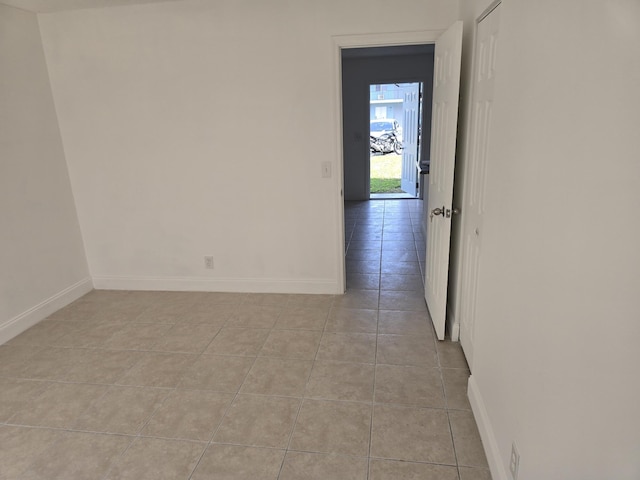 spare room with light tile patterned flooring and baseboards