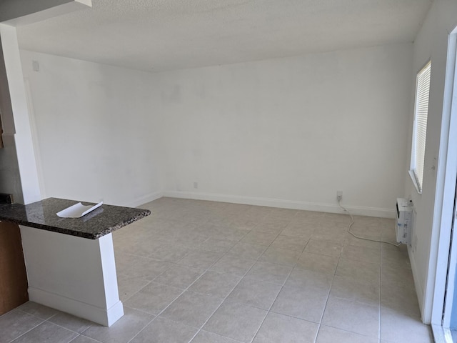 spare room featuring a wealth of natural light, a wall mounted air conditioner, baseboards, and light tile patterned floors