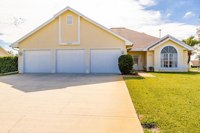 view of front of home with an attached garage, driveway, a front lawn, and stucco siding