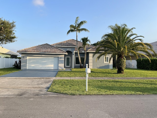 view of front of home featuring stucco siding, concrete driveway, an attached garage, a front yard, and fence